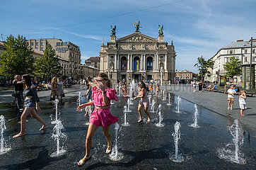 Ukraine  Lwiw - Kinder und Jugendliche erfrischen sich an Wassersauelen vor der Oper am Prospekt Svobody