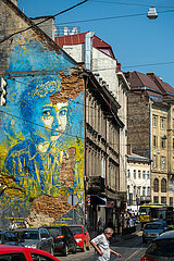 Ukraine  Lwiw - Verkehr auf einer Hauptstrasse im Stadtzentrum und Wandbild mit einem Maedchen in ukrainischen Farben