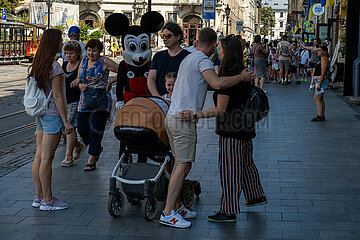 Ukraine  Lwiw - Menschen flanieren am Marktplatz (ukrainisch Rynok  Altstadt seid 1998 auf der UNESCO-Liste des Weltkulturerbes)  dabei Mann als Mickey Mouse verkleidet