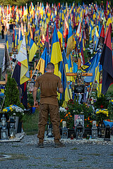 Ukraine  Lwiw - Das Marsfeld  Ehrenfriedhof der gefallenen Lwiwer Soldaten im Ukrainekrieg  Soldat am Grab eines Kameraden