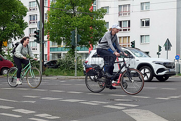 Berlin  Deutschland  Radfahrer und Auto fahren die Petersburger Strasse entlang