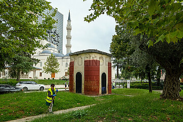 Albanien  Tirana - Staedtische Angestellte beim Laubharken in einem Park im Zentrum  hinten die Namazgah-Moschee und Hochhaus