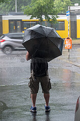 Berlin  Deutschland - Mann mit Schirm im Sommerregen