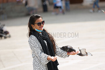 Venedig  Venetien  Italien  ITA - Am San Marco Platz haelt eine Frau eine Taube auf der Hand