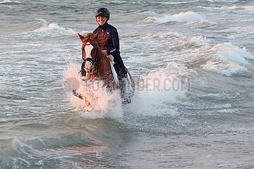 Dierhagen  Frau reitet auf ihrem Pferd durch das Wasser der Ostsee